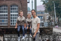 a man and his two children are posing on a railing