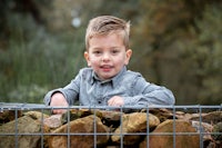 a young boy leaning over a fence