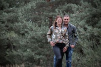 a man and a woman standing in a wooded area